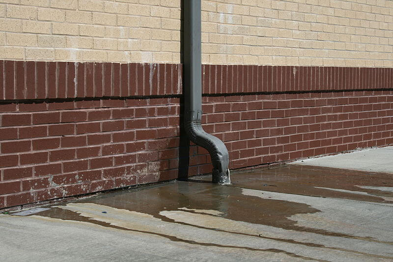 broken downspouts edmonton installation on white brick wall with leaking water in edmonton